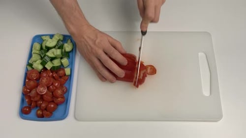 Mann schneidet Paprika mit einem Messer. Ansicht von oben nach unten. Hobbykoch