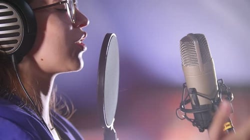 Woman Singing with Headphones in Music Recording Studio