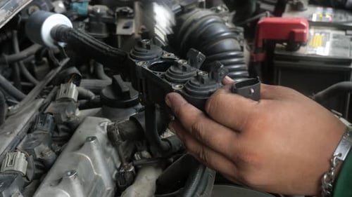 A close-up shot of a mechanic's hands while working on the engine of a vehicle in a repair shop in B