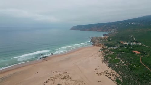 Água azul do mar incha até uma praia arenosa ladeada por penhascos imponentes. Vista de Drone