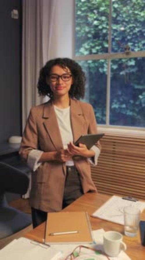Femme d'affaires confiante debout dans un bureau moderne et lumineux tenant une tablette numérique