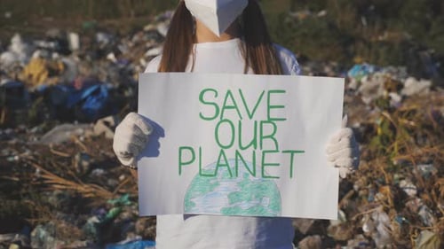 Child Holding Environmental Sign at Landfill