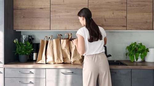 Woman Unpacking Groceries in Modern Kitchen