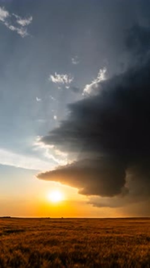 Dramatic sunset over golden field with storm clouds