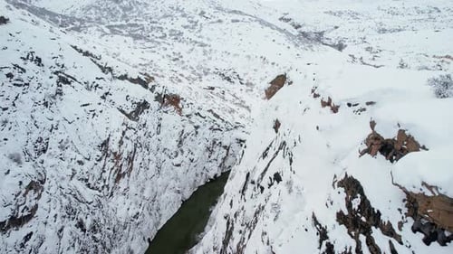 Winterschlucht mit Fluss, der zwischen verschneiten Klippen fließt