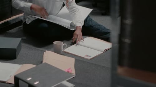 Young Adult Woman Reviewing Documents on Floor