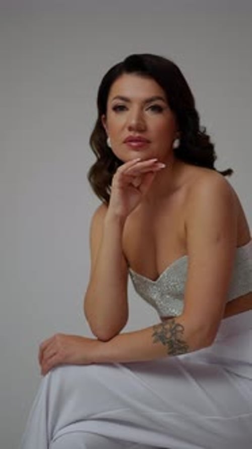 Luxurious Brunette in Shiny Clothes on a White Background