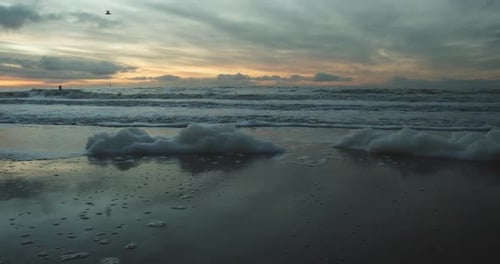 Foam washed up on the beach of Sylt with the sunset in the background
