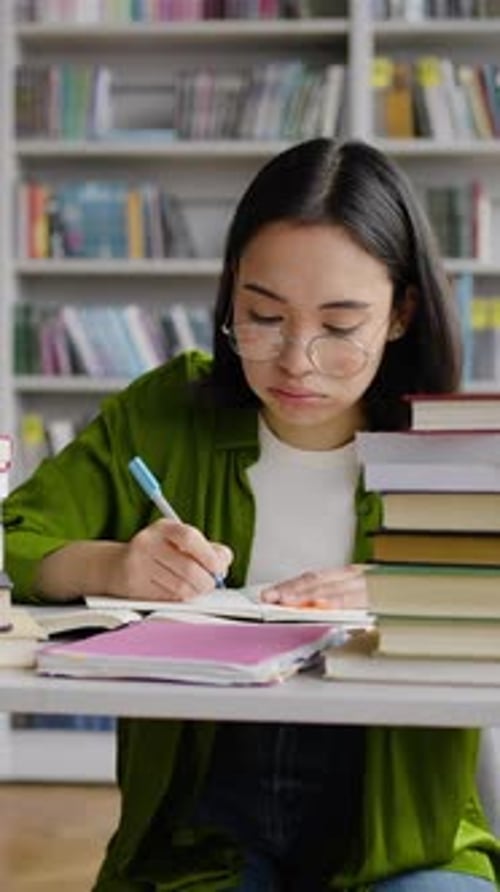 Young Teacher Works with Books Taking Notes in Library