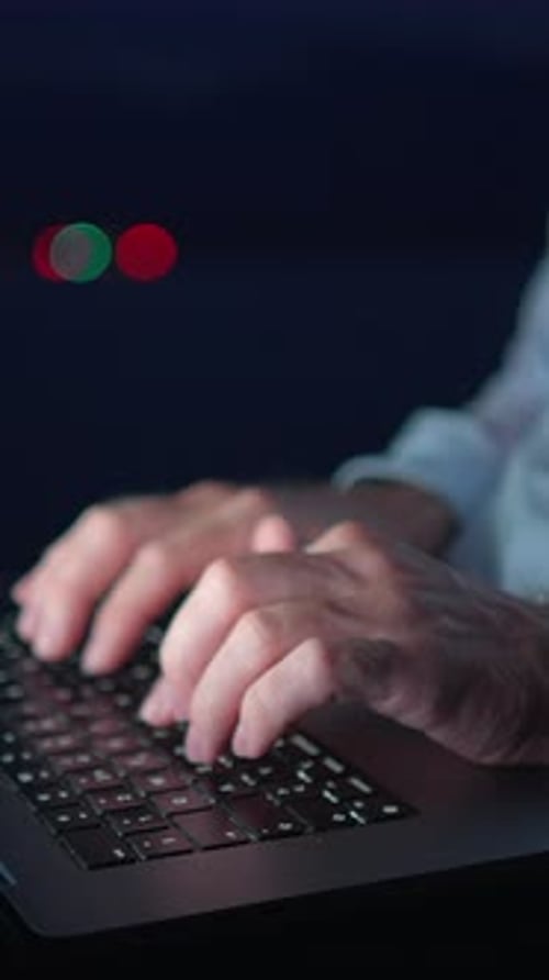 Hands Typing on Laptop Keyboard in Dark Setting