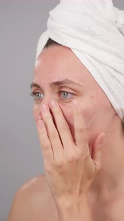 Calm Beautiful Woman Applying Facial Moisturizer on Studio Grey Background