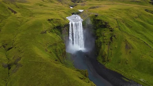 cinematic drone footage of Skógafoss Waterfall in Iceland, capturing the immense curtain of water