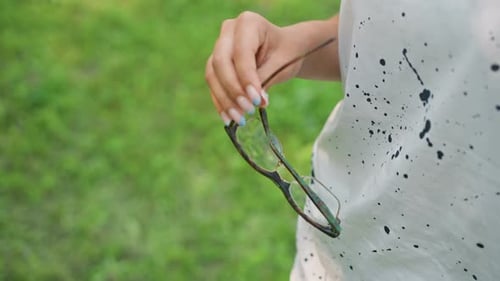Mulher relaxada estende óculos de sol em um parque verde durante o verão. Mulher vestida casualmente chega