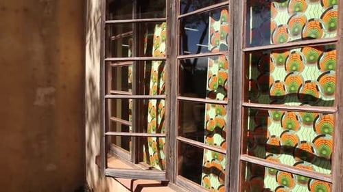 Colorful decorative curtains inside building by glass windows gently move in the breeze, Tanzania, s
