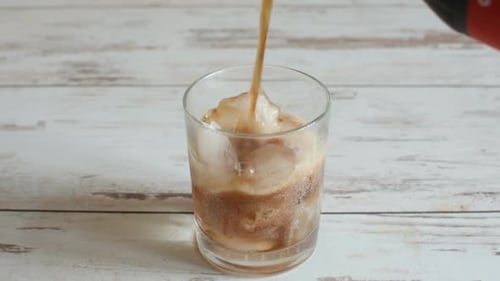 Pouring Dark Soda into Ice Filled Glass