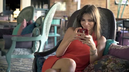 Woman Relaxing Indoors Using Smartphone in Armchair