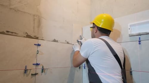 Construction Worker Laying Tiles in a Bathroom