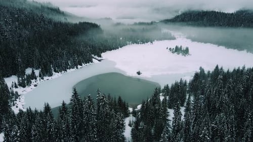 Stunning Lake Aerial In Snowy Mountain Forest With Moody Fog Haze