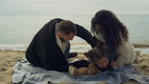 Playful family tickling daughter on summer vacation at the sea beach shore