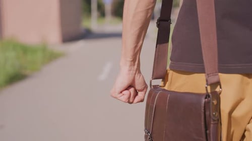 Man with Brown Bag Walking on Sidewalk