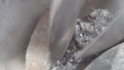 Molten lead being poured into a mold with visible steam, close up