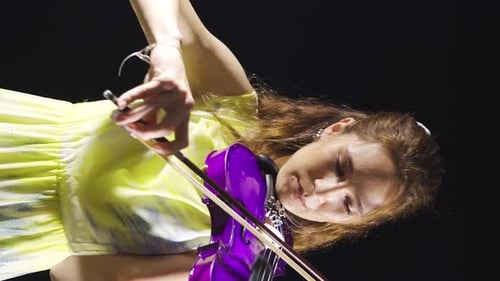Woman Plays a Purple Violin in Dramatic Lighting