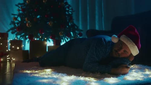 Un garçon dort sur le tapis en attendant le Père Noël le soir de Noël dans la chambre