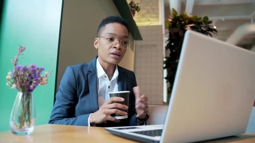 African American female holds an online meeting uses a laptop for a video call, works in a cafe,