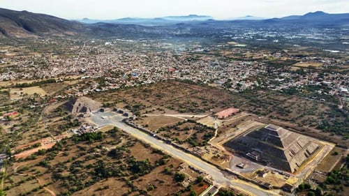 Aerial drone view of the ancient Teotihuacan pyramids with the surrounding Mexican town and mountain