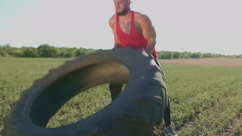 Muscular CrossFit Man Lifting a Wheel Outdoors