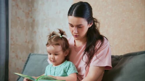 Woman Reading with Child Indoors on Couch