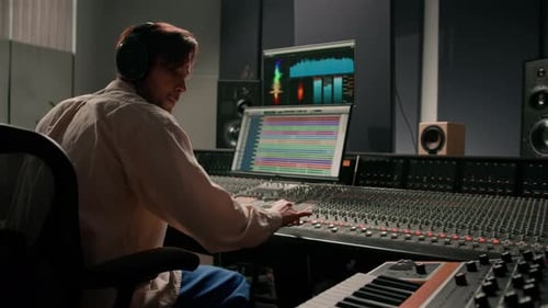Energetic audio engineer producer working in recording studio mixing tracks on console and hit maker
