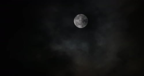 Full Moon Glowing Behind Passing Clouds at Night