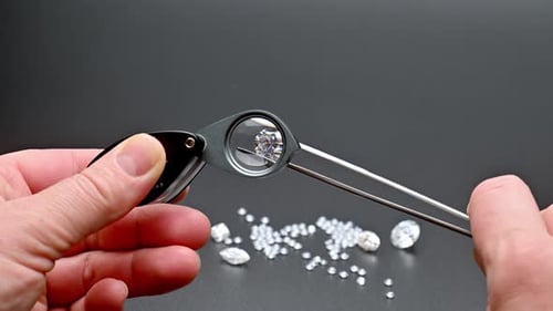 Person uses magnifying instrument to examine diamonds