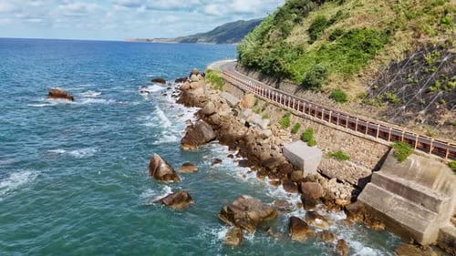 Scenic Coastal Road with Ocean Waves Crashing Against Rocky Shoreline