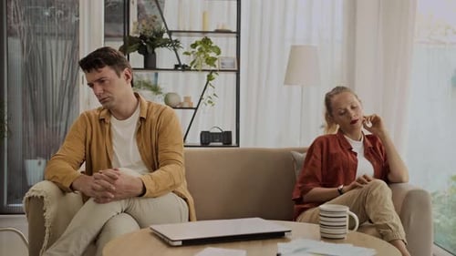 Couple Sitting Separately on Couch Looking Unhappy