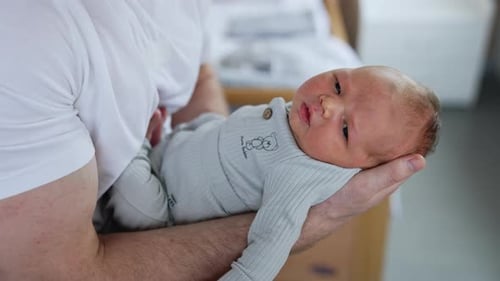 Parent Holds Newborn Baby Tenderly Indoors