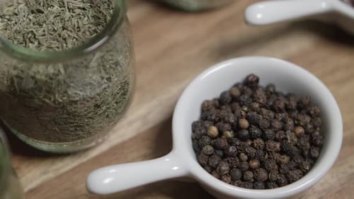 Close up panning shot of thyme and black pepper sitting in small jars. The ingredients are ready for
