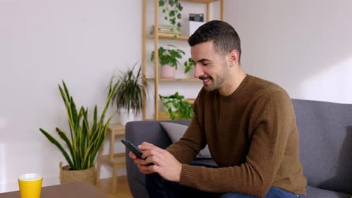 Man Using Smartphone on Sofa in Home