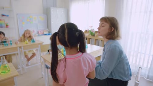 Adorable student learn with teacher in classroom at elementary school.