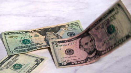 American money falling onto a marble countertop.