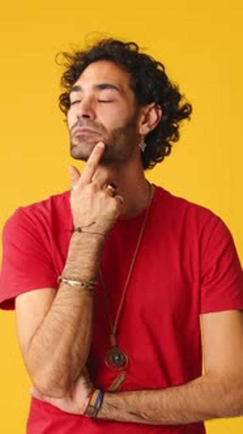 Pensive man rubbing his chin and looking side isolated on yellow background in studio
