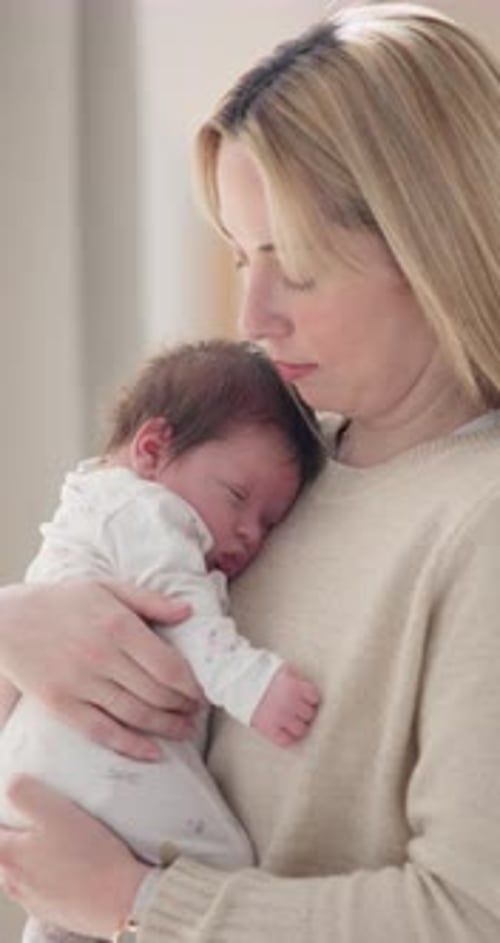 Mother Holding Sleeping Infant in a Home