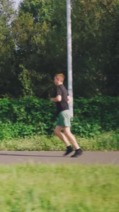 Running Cardio Workout Young Caucasian Man Runs in the Morning in the City Park with Lush Vegetation