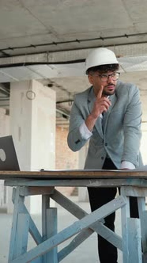 Architect Using Laptop and Reviewing Blueprints on Construction Site