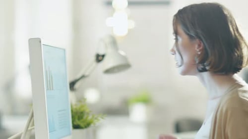 Young Beautiful Woman Returns to Her Work Place and Sits at Her Computer Desk.