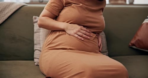 Pregnant Woman Gently Rubbing Stomach at Home