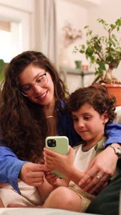 Woman and Child Looking at Smartphone Together Indoors