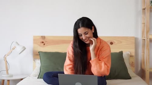 Happy Young Woman Using Laptop on Bed