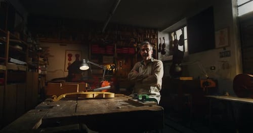 Cinemática de un maestro luthier artesano profesional que sonríe satisfecho con su trabajo ante la cámara